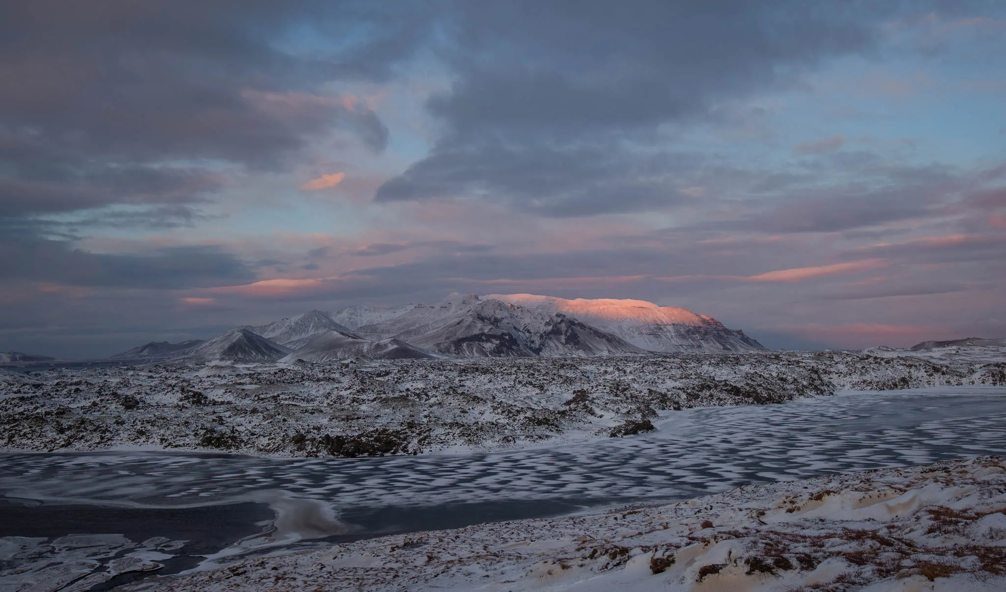 Snow-covered mountain landscape beneath a softly coloured winter sky
