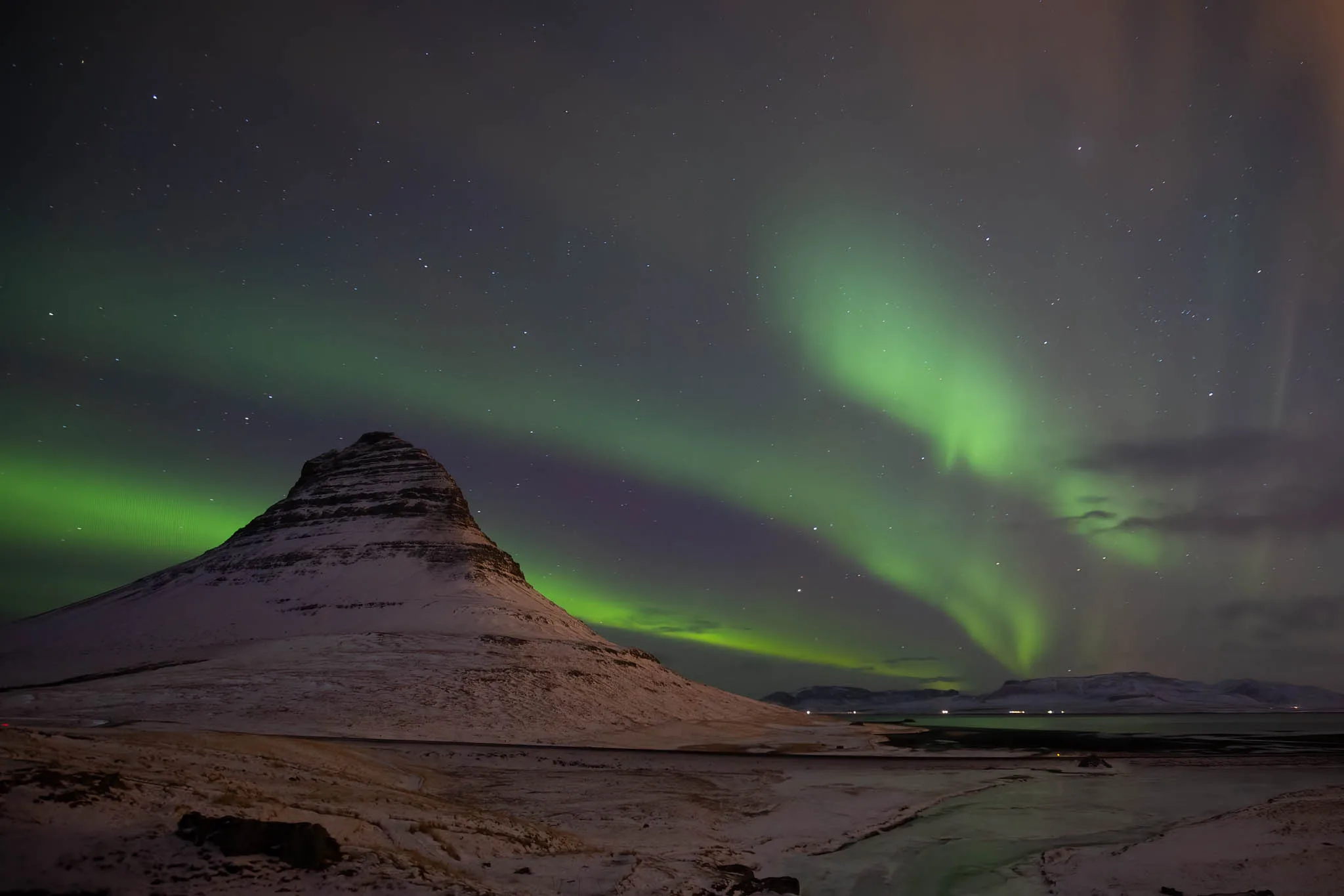 Green aurora borealis sweeping across the sky above Kirkjufell mountain in Iceland