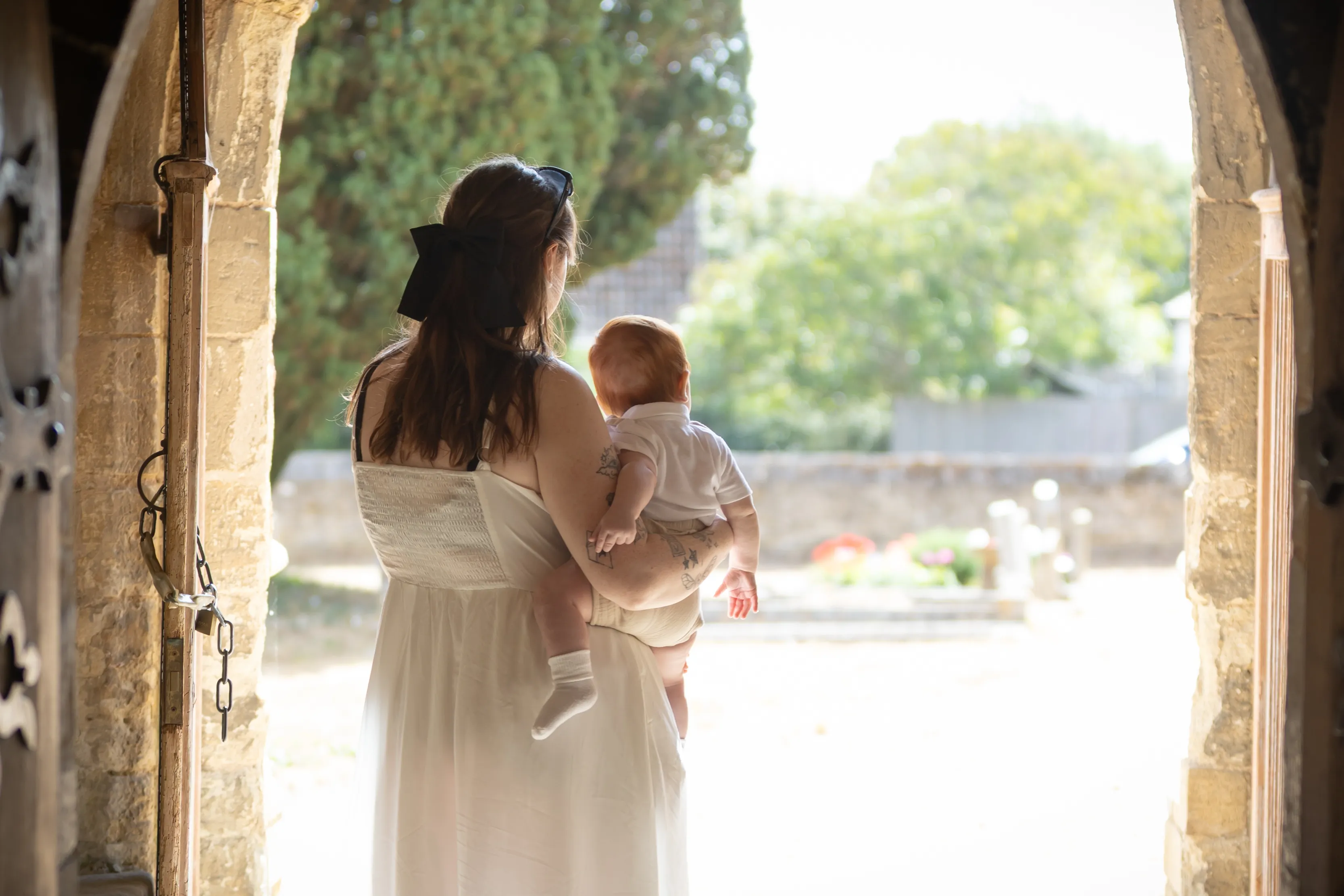 Mother carrying her child through a sunlit church doorway