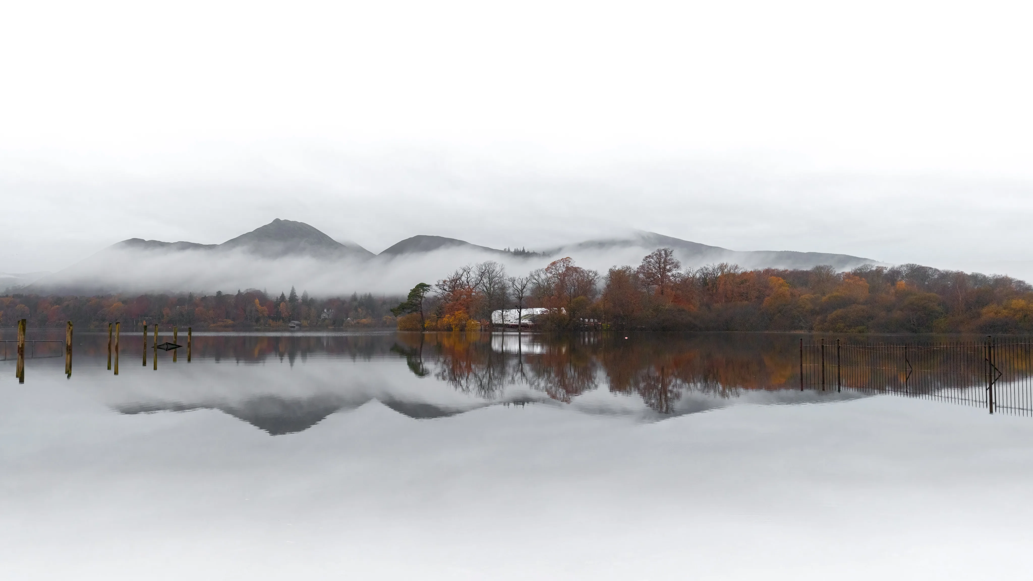 Distant mountains and woodland reflected in the Lake District
